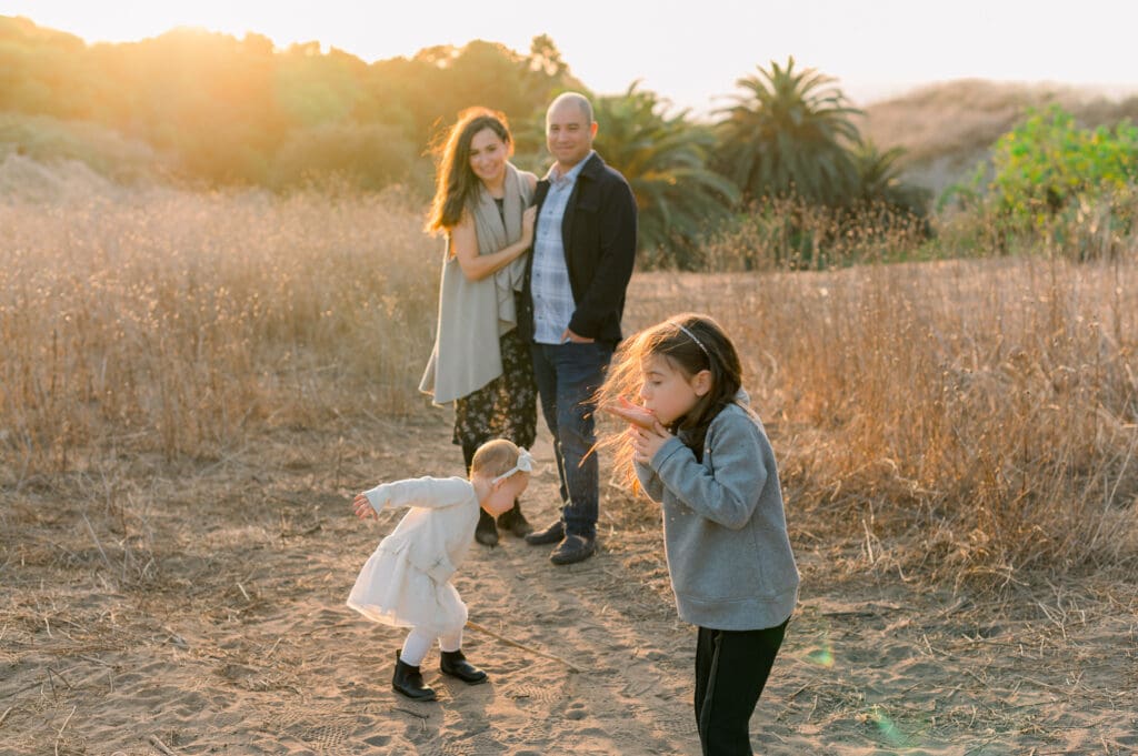 A mom and dad watch their girls play during a fall family photo session.