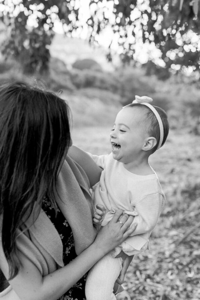 A little girl laughs in her mom's arms.