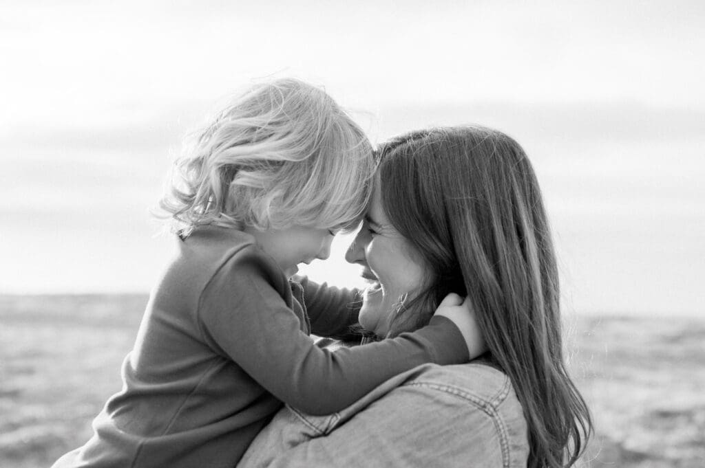 A mom and son smile and put their foreheads together.