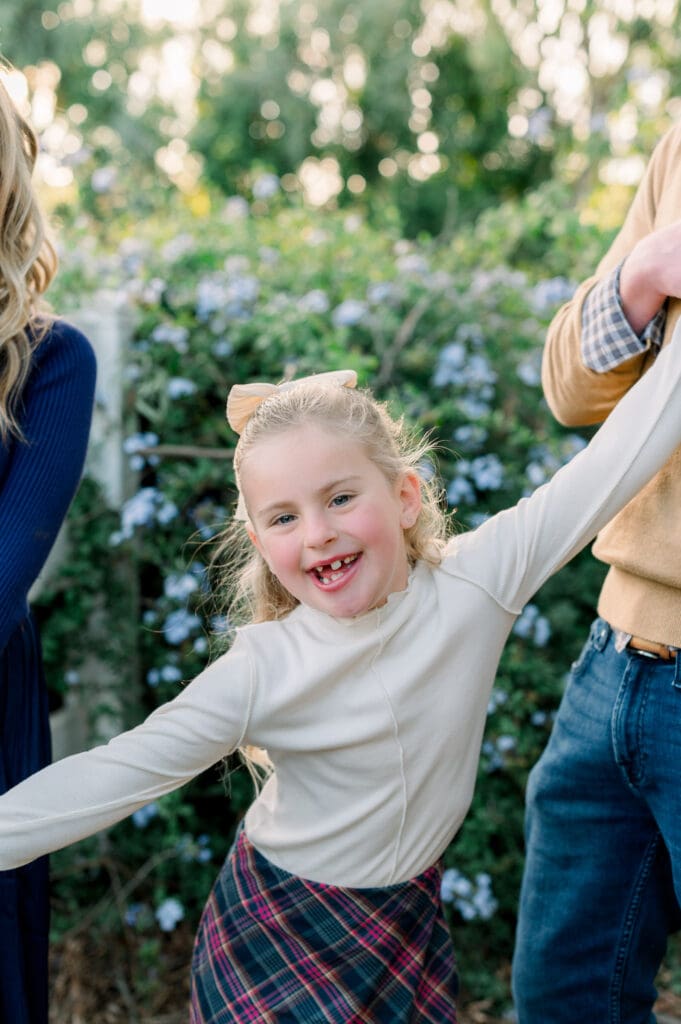 A young girl smiling big with her parents during their fall family photos.