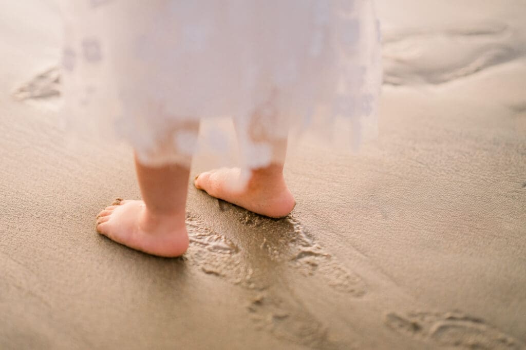 A close up of a little girl's feet in the sand.