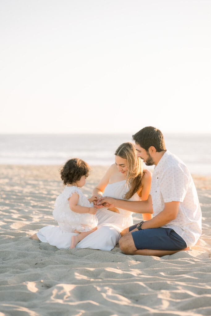 A Manhattan Beach family photographer captures a sweet moment of a family looking at shells on the beach.