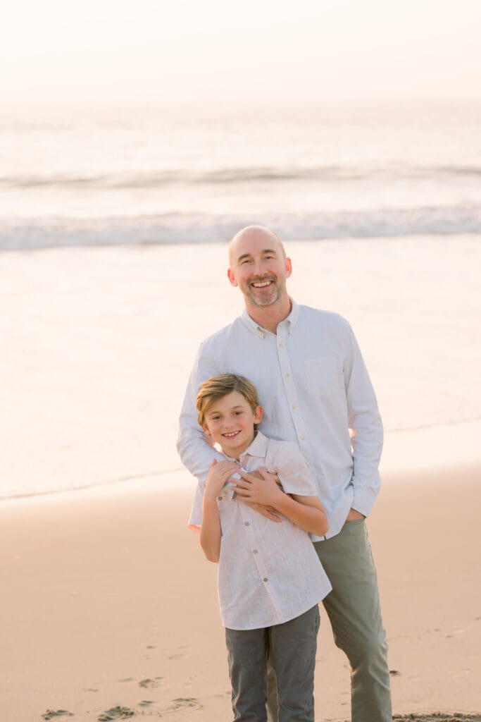A dad and son posing for family beach photos.