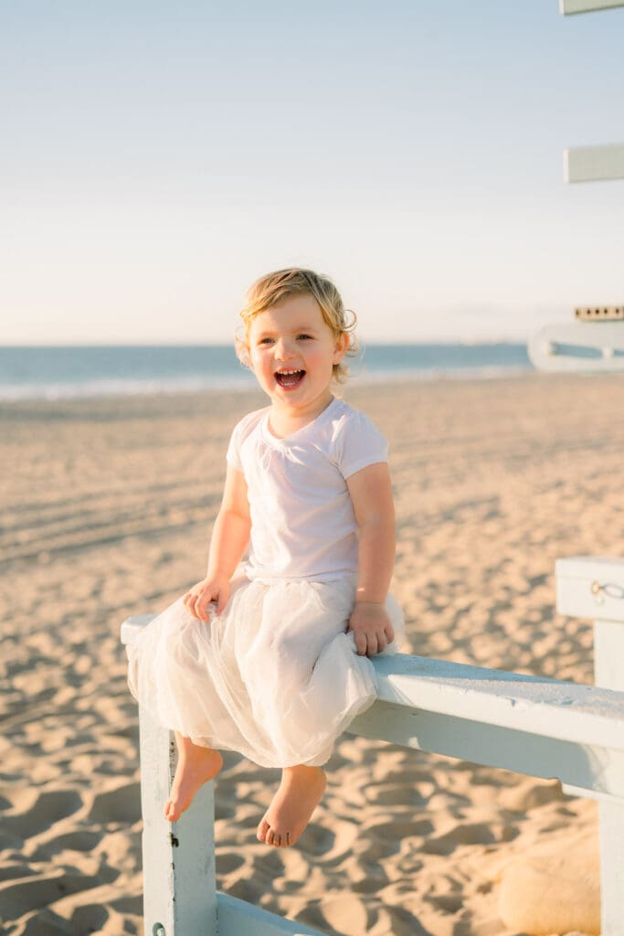 A little girl in a white shirt and skirt taking family beach photos.