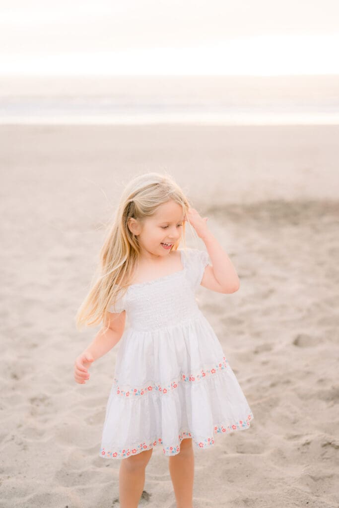 A little girl in a white dress showing what to wear for family beach photos in the South Bay.