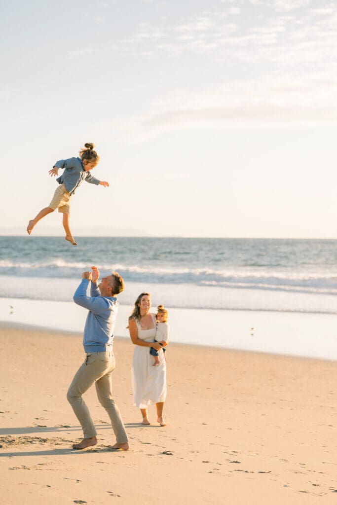 A family playing on the beach, an example of what to wear for family beach photos.