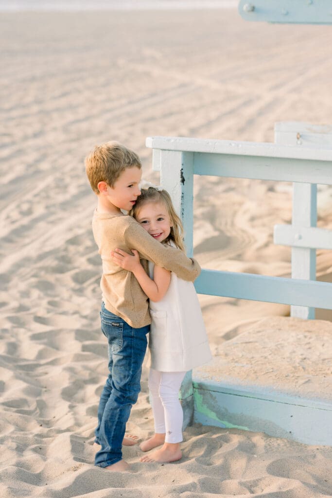 Siblings hugging on the beach for family photos.