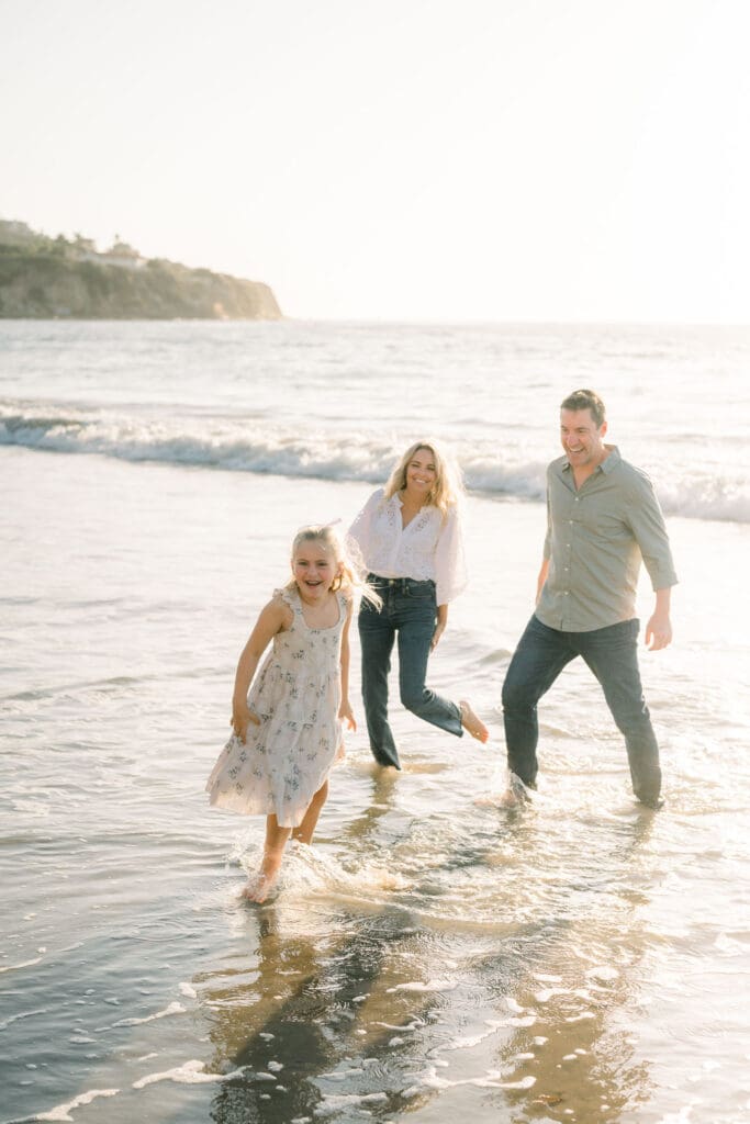 A family playing in the water while taking family beach photos at sunset in the South Bay.