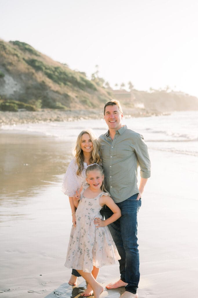 Mom, dad, and little girl posing on the beach for family beach photos in the South Bay.