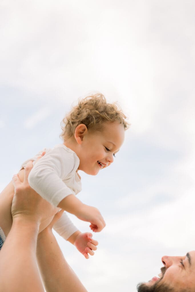 Dad holding his toddler son up in the air.