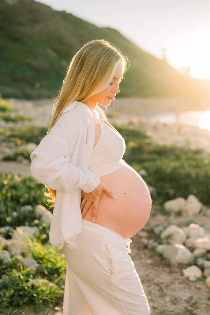 A golden hour photo of a pregnant woman taking casual beach maternity photos in the South Bay.