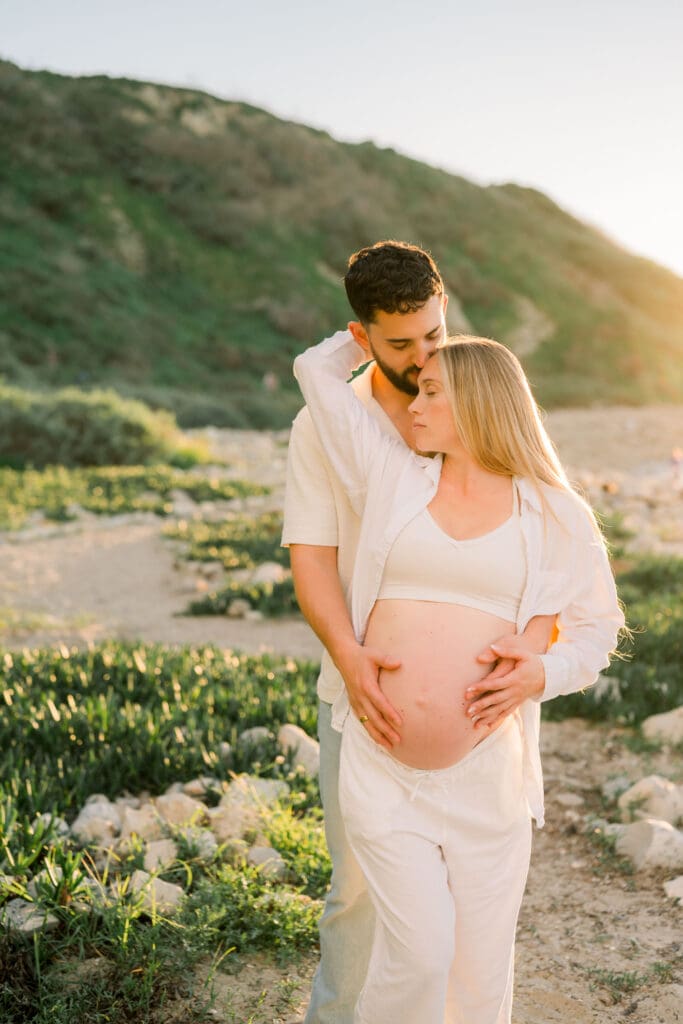 A couple posing for maternity photos on a South Bay beach.