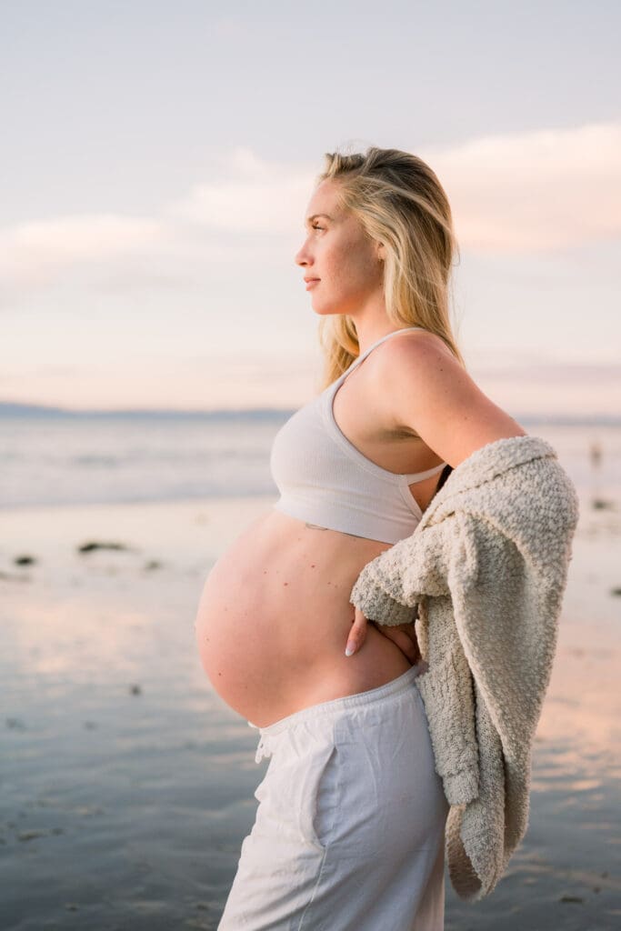 A pregnant woman posing for maternity photos on a South Bay beach.