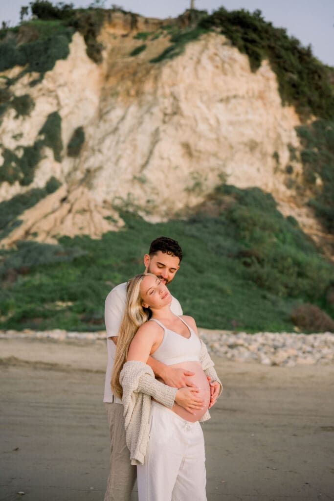 A couple does a maternity photo shoot on the beach.