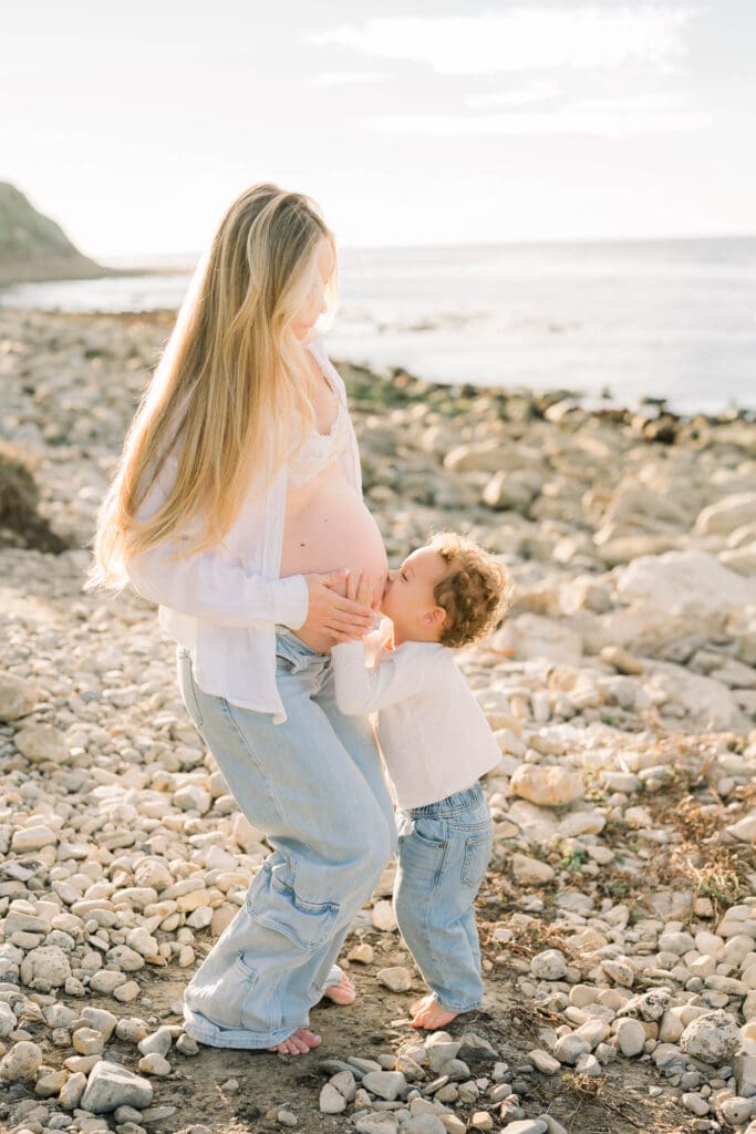 A little boy kisses his mama's pregnant belly while taking casual beach maternity photos in the South Bay.