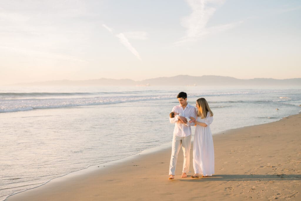A new family of 3 walking on the beach at golden hour in Hermosa beach.