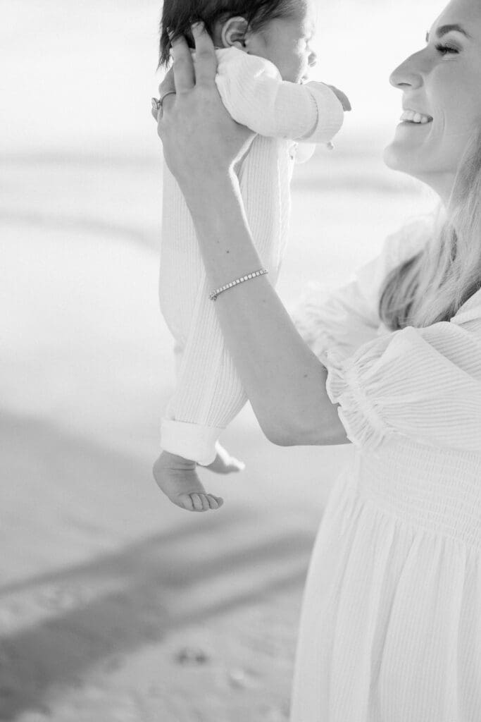 Hermosa Beach newborn photographer takes a black and white photo of a mom holding up her newborn baby.