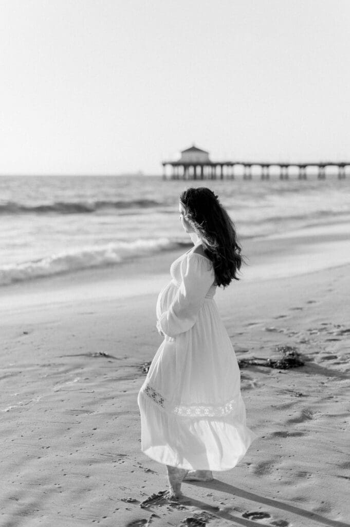A pregnant woman posing for maternity photos at the Manhattan Beach pier.