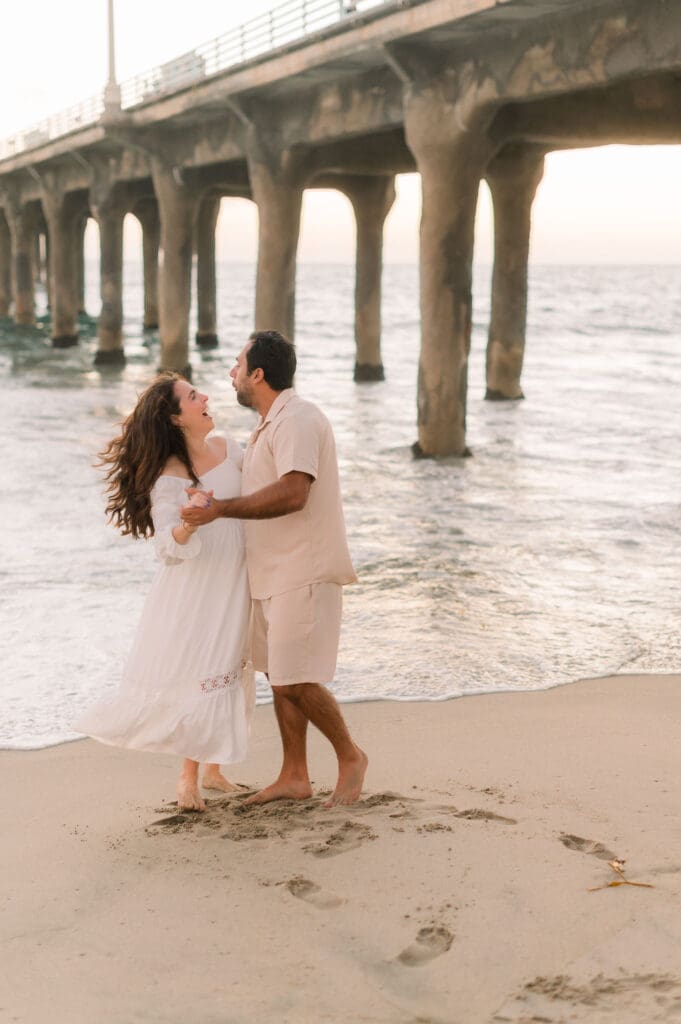 A couple dancing in front of the Manhattan Beach pier while taking maternity photos.