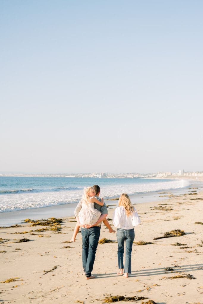 A family walks down the beach during their beach family photography session in Los Angeles.