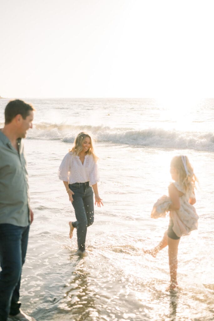 A family playing in the ocean during their beach family photography session in Los Angeles.