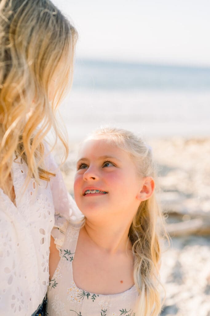 A mom and daughter looking at each other on the beach while taking family photos in Los Angeles.