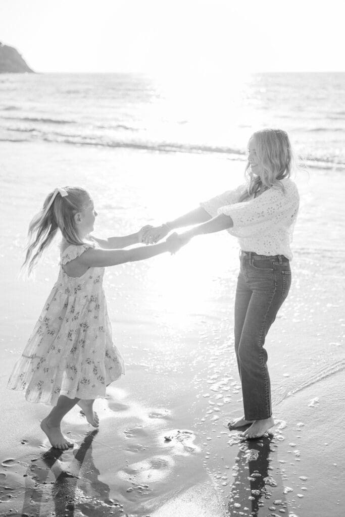 Mom and daughter spinning on the beach together during their beach family photography session in Los Angeles.