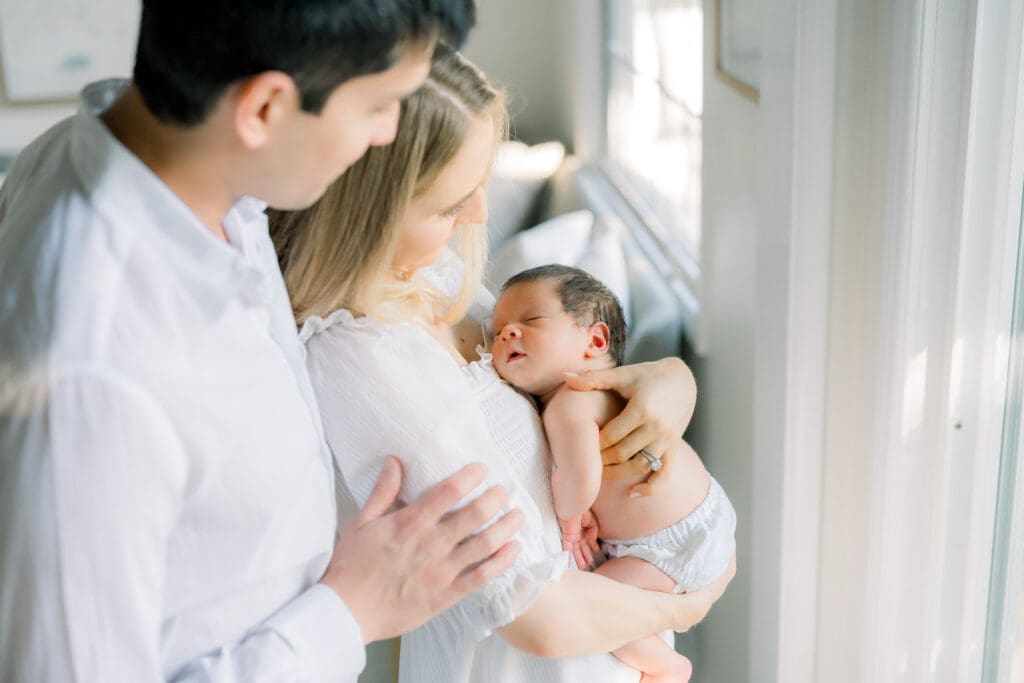 A mom and dad stare at their sleeping baby during their in home newborn photography session in Los Angeles.