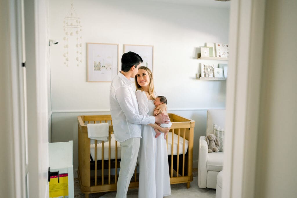Mom and dad looking at each other and holding their newborn baby at home.