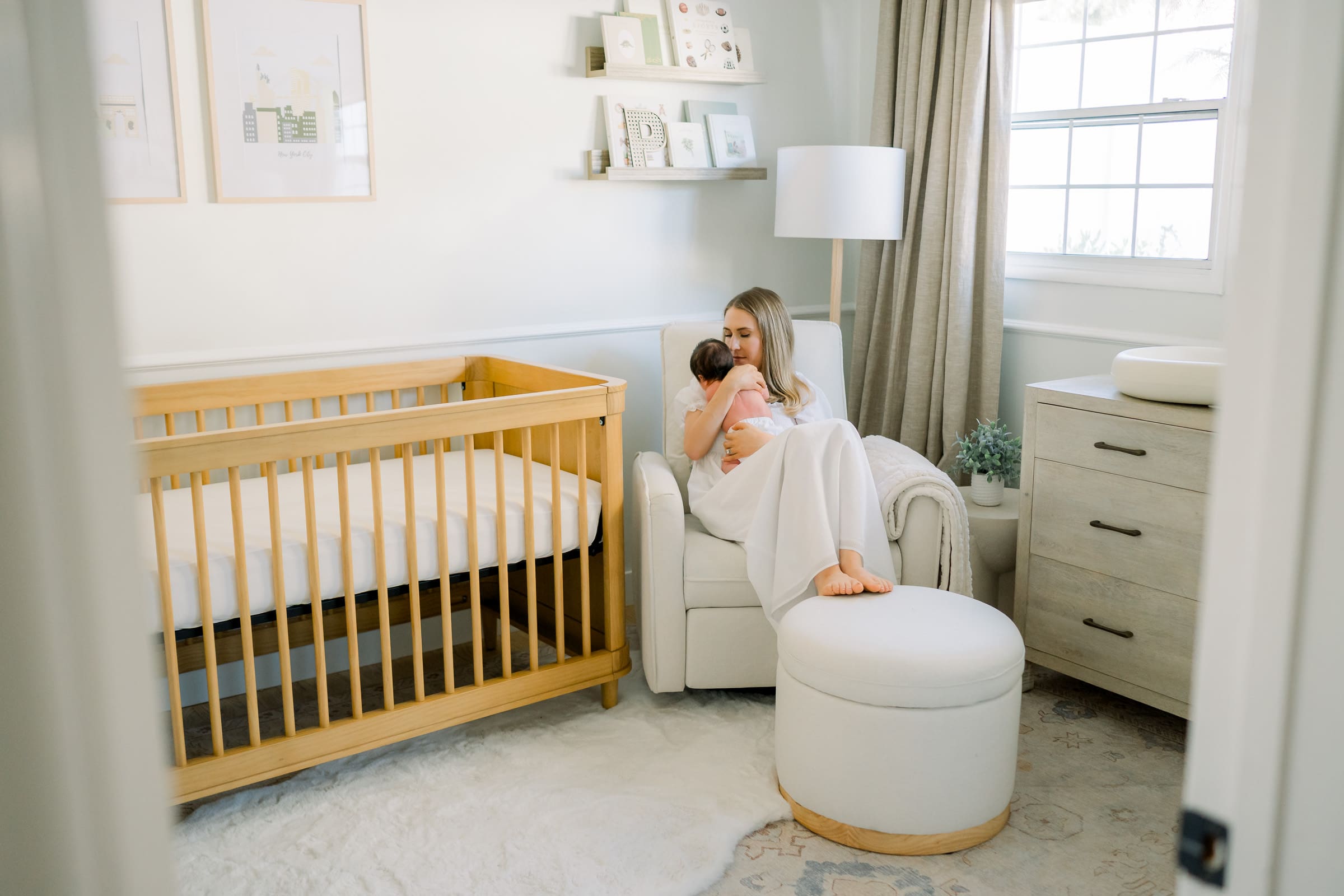 A mother holding her newborn baby in the nursery chair during an in home newborn photography session.