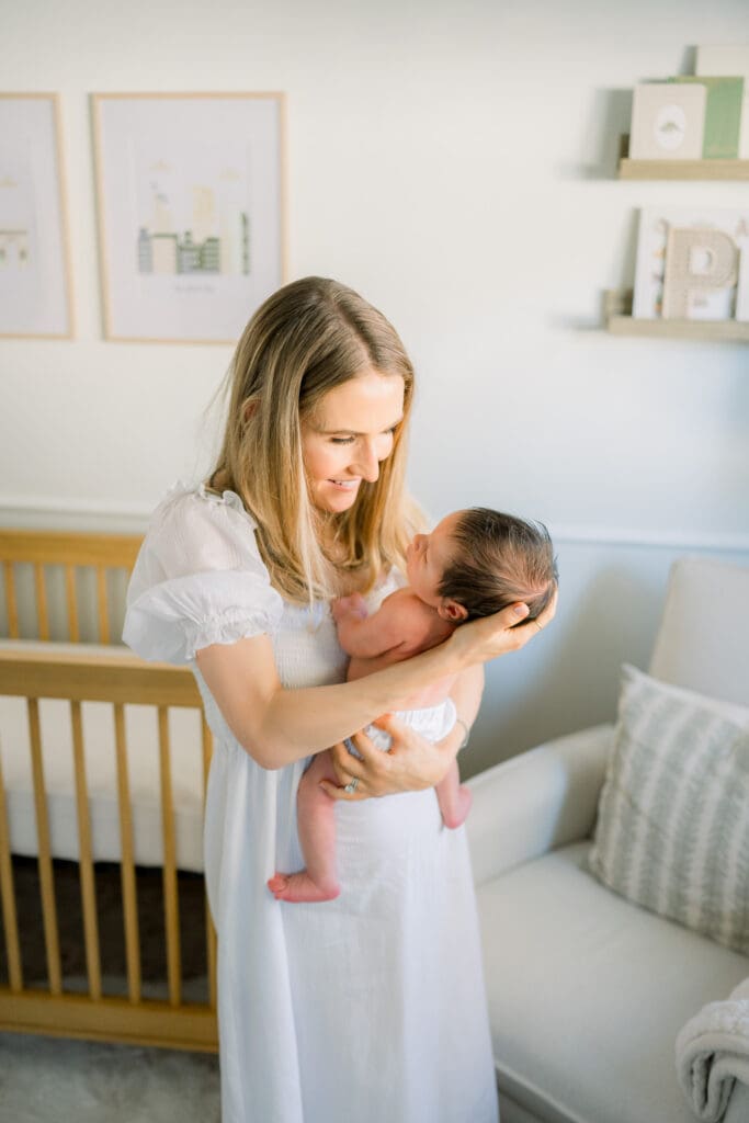 A mom holding her newborn son in his nursery at home.