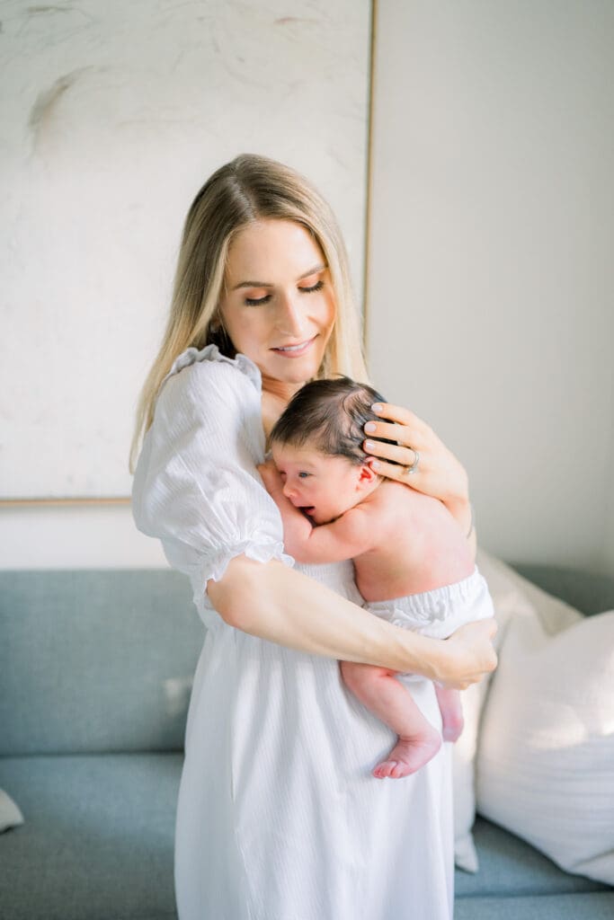 A mother holding her newborn son while taking in home newborn photos in Los Angeles.