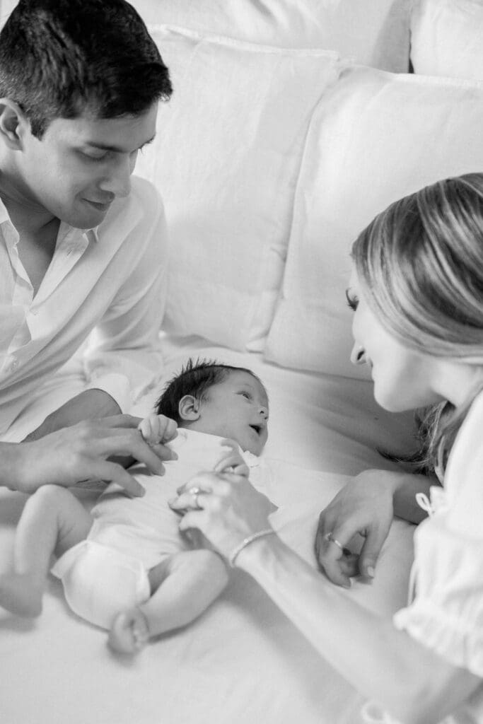 Mom and dad playing with their baby on their bed.