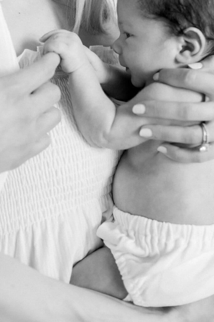 A baby holds his mom's finger during an in home newborn photography session in Los Angeles.