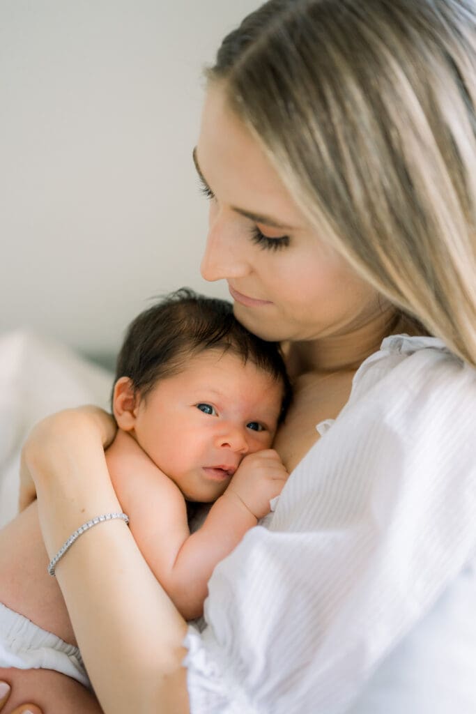 A mom lovingly holds her newborn baby close to her chest.