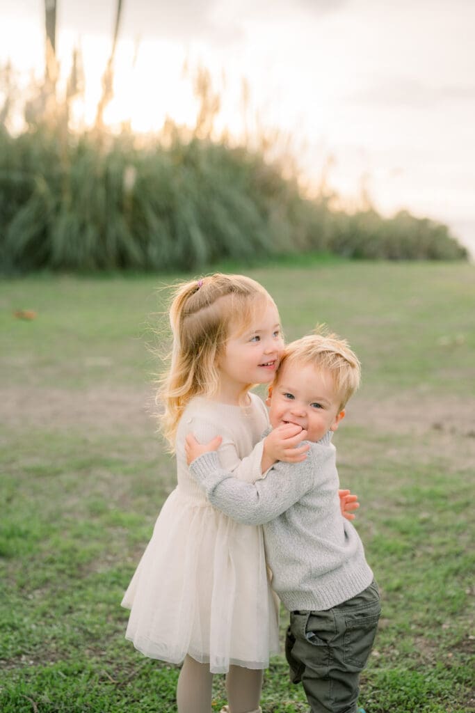 A little girl hugs her baby brother at their family photo session in Palos Verdes at sunset.