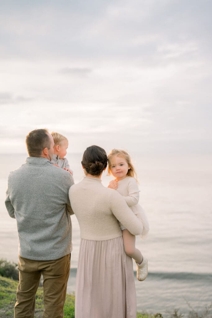 A family of 4 looking out at the sunset together at the Palos Verdes cliffs.