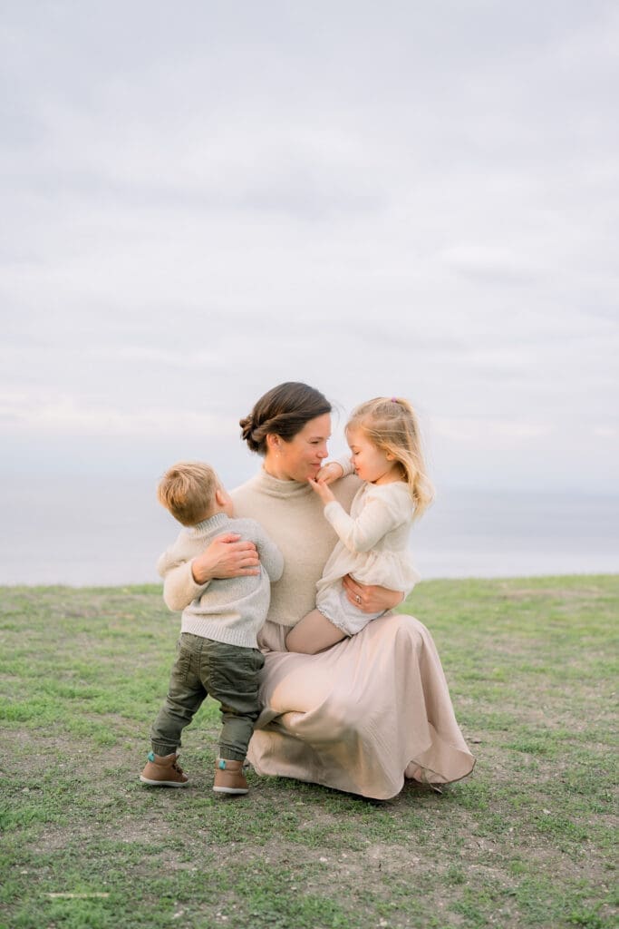 A mom holds her 2 young children lovingly as they take family photos at the Palos Verdes cliffs.