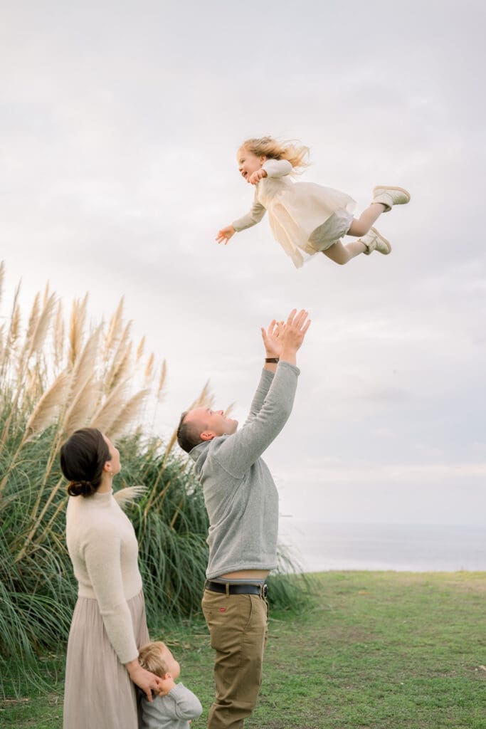 A dad throws his young daughter up in the air during their family photo session in Palos Verdes.