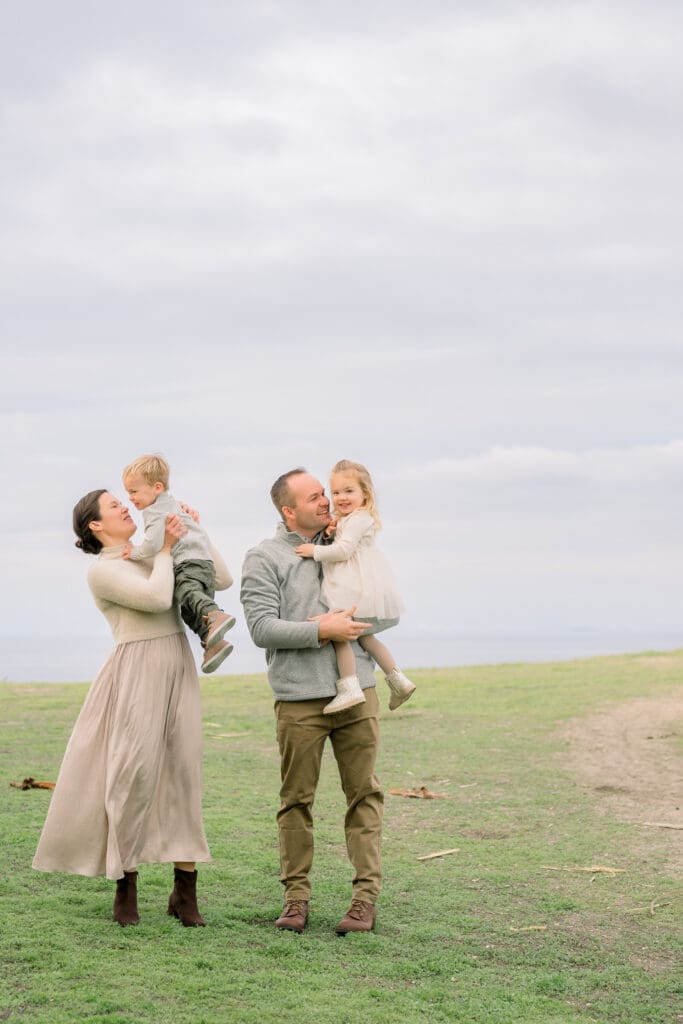 A family of 4 snuggled up and playing during their family photos at the Palos Verdes Cliffs.
