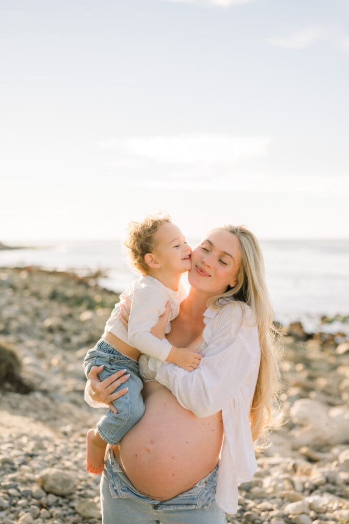 A pregnant mom wearing jeans, a bralette, and white button up shirt for her maternity photos with her son, who is wearing jeans and a t-shirt.