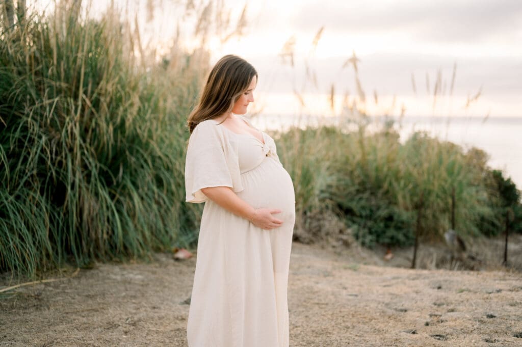 A mother to be wearing a cream flowy dress for her maternity photos in Los Angeles.