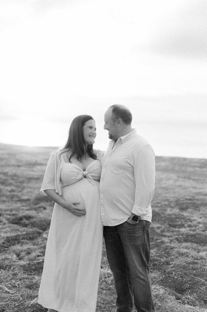 A maternity photo of a couple looking at each other lovingly.