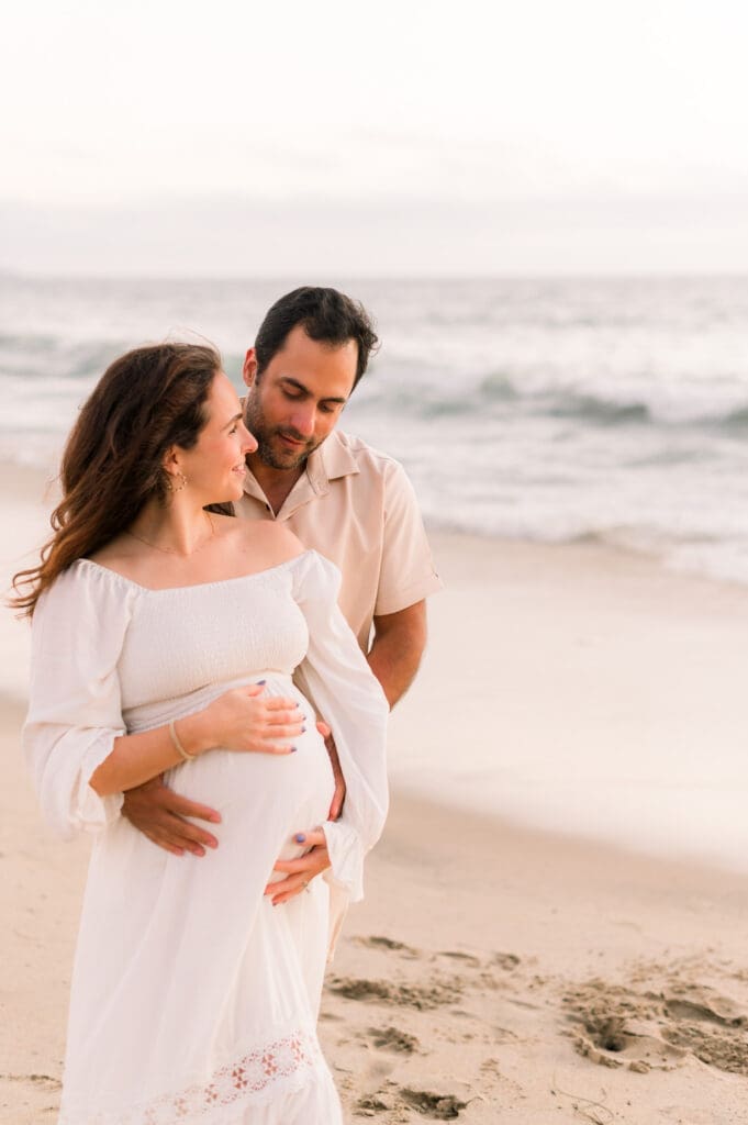 A favorite maternity photography pose of a couple with their arms wrapped around each other.