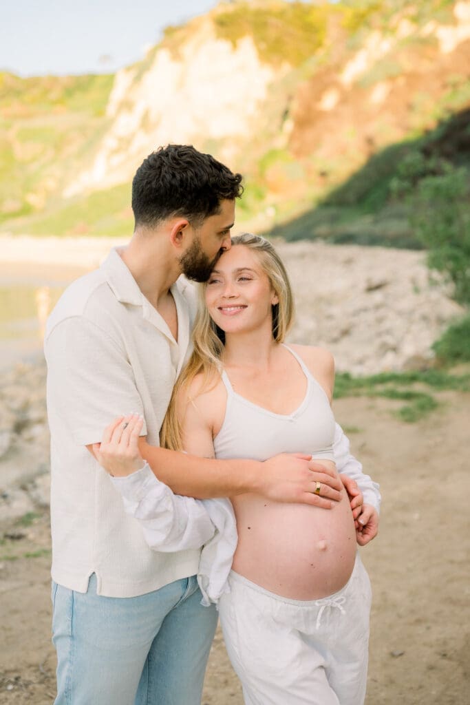 A man kissing his wife's forehead during their Los Angeles maternity session.