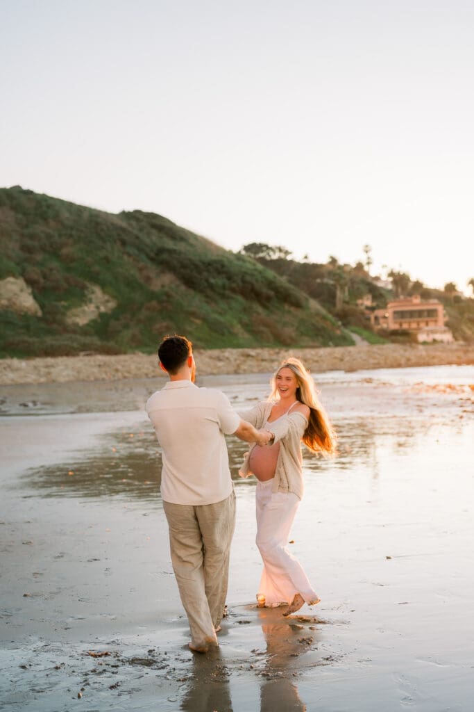 A couple dancing on the beach at sunset.