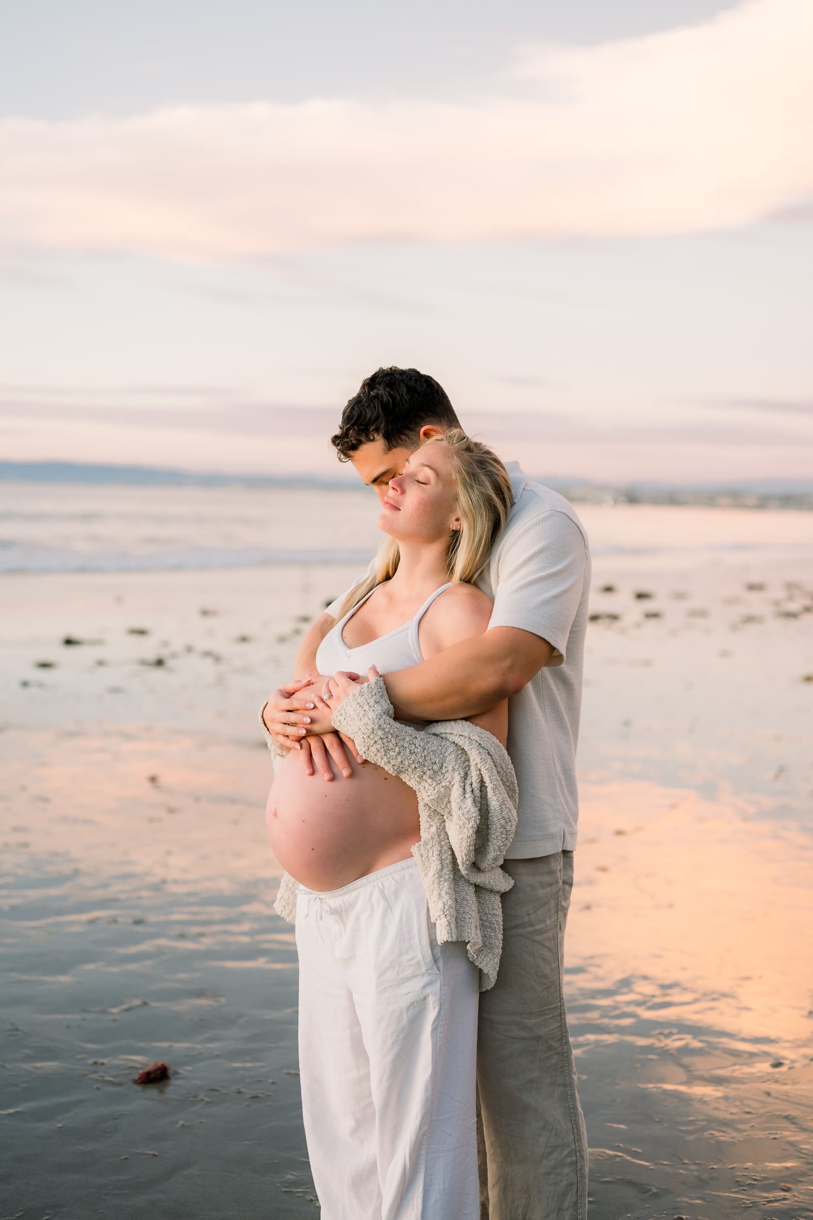 A couple poses on the beach for their Los Angeles maternity session.