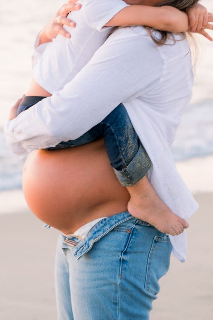A close up shot of a pregnant mom holding her young son while they take maternity photos.