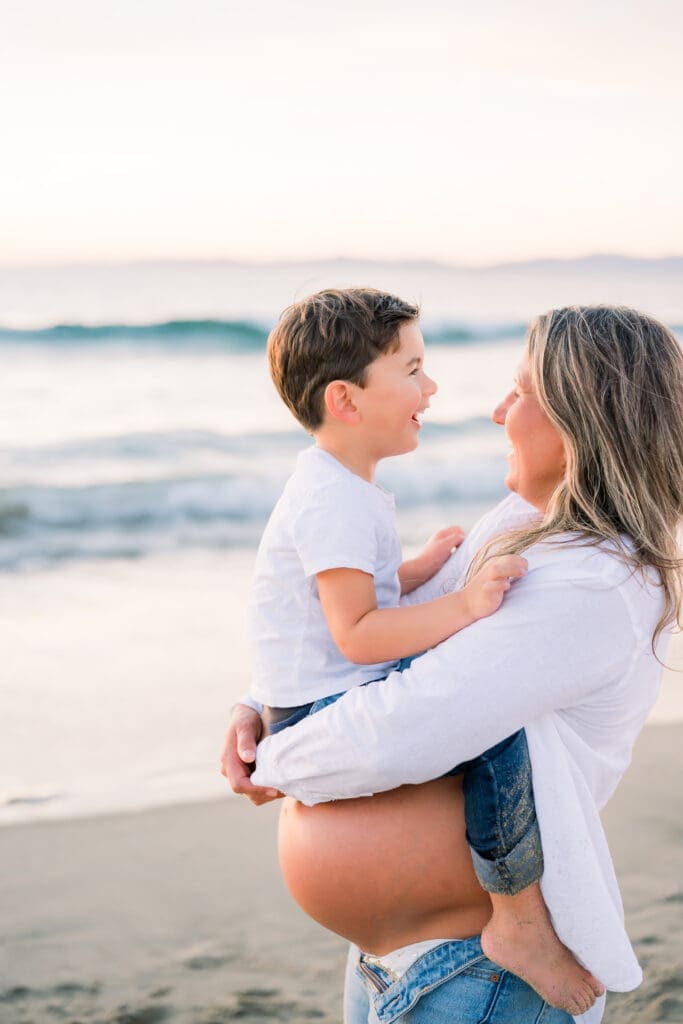 Mom holding her son on top of her pregnant belly.