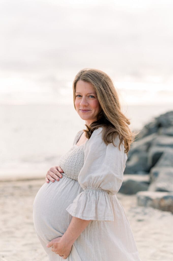 A must-have maternity photo of a mom holding her bump on the beach.